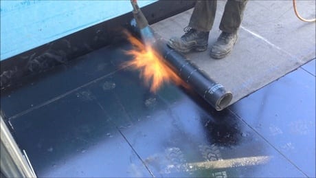 A photo of a man waterproofing a roof